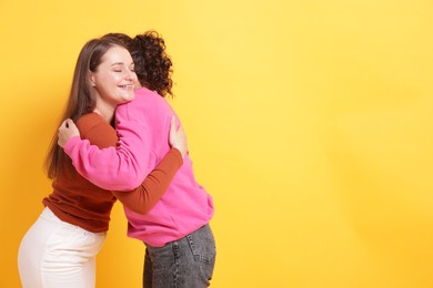 Photo of Friends hugging each other on orange background, space for text