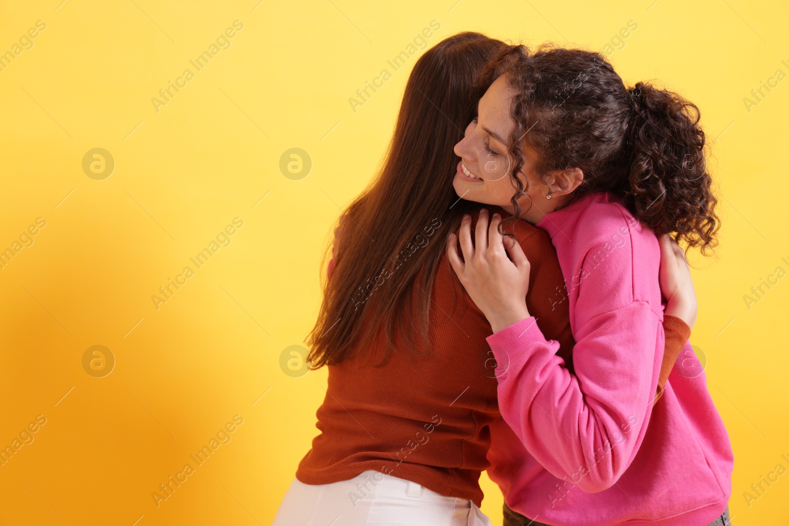 Photo of Friends hugging each other on orange background, space for text