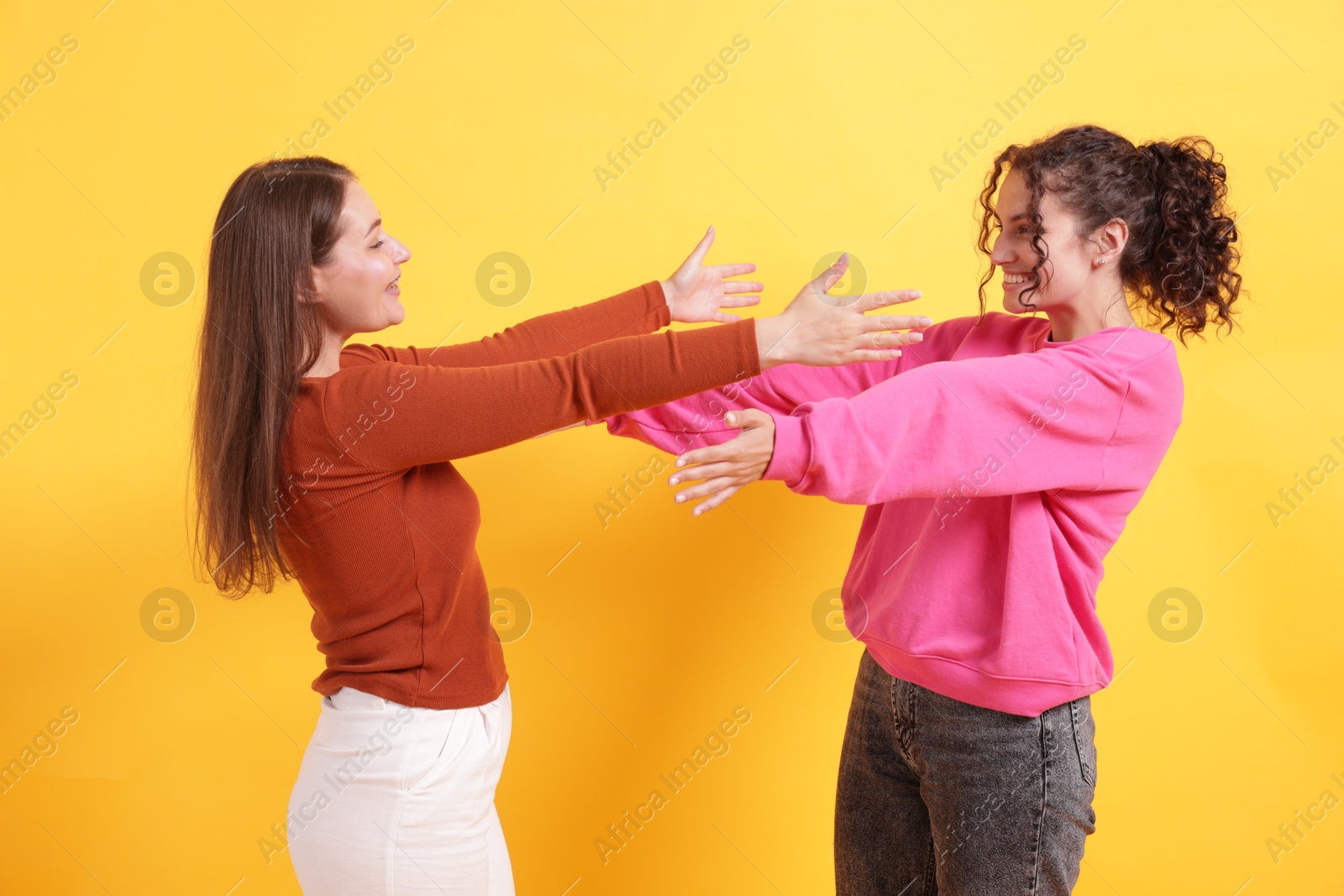 Friends welcoming each other on orange background Photo of Friends welcoming each other on orange background