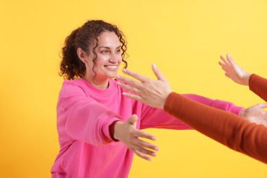 Photo of Friends welcoming each other on orange background, closeup