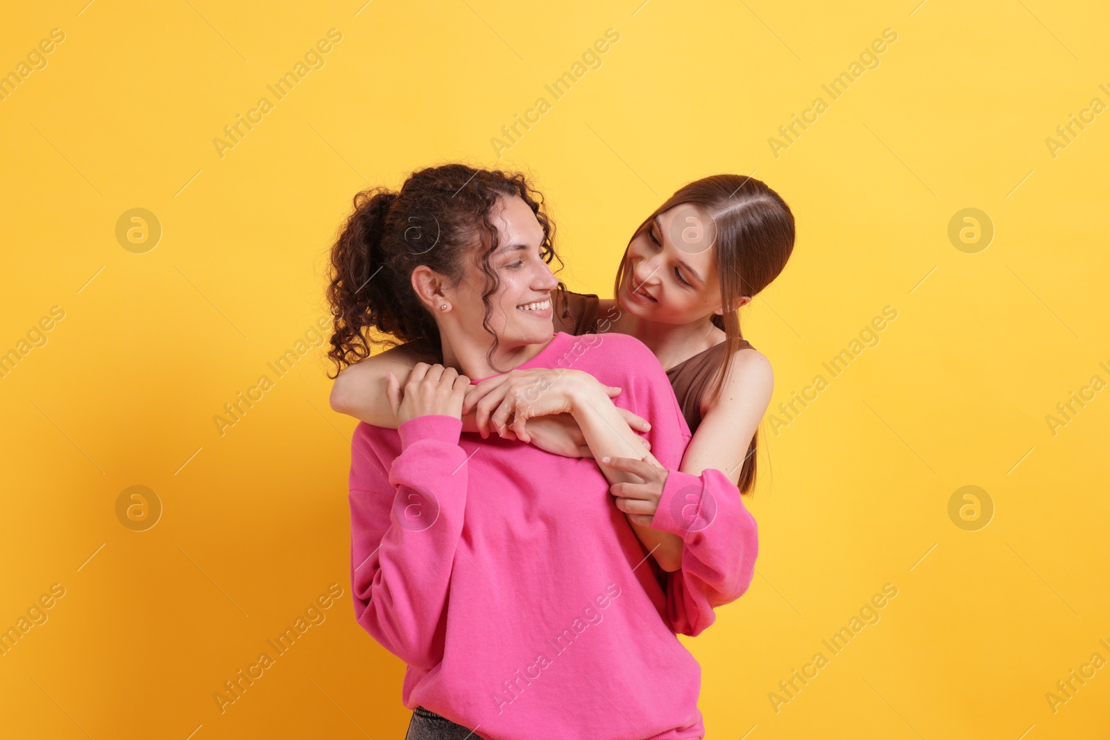 Friends hugging each other on orange background Photo of Friends hugging each other on orange background