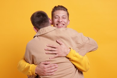 Photo of Friends hugging each other on orange background