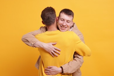 Photo of Friends hugging each other on orange background