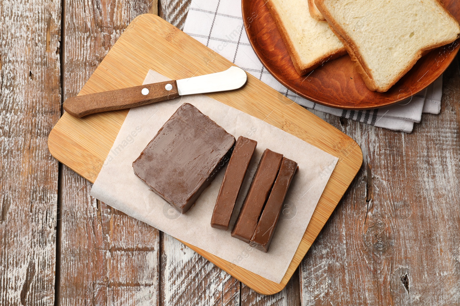 Tasty chocolate butter, slices of bread and knife on wooden table, flat lay Photo of Tasty chocolate butter, slices of bread and knife on wooden table, flat lay