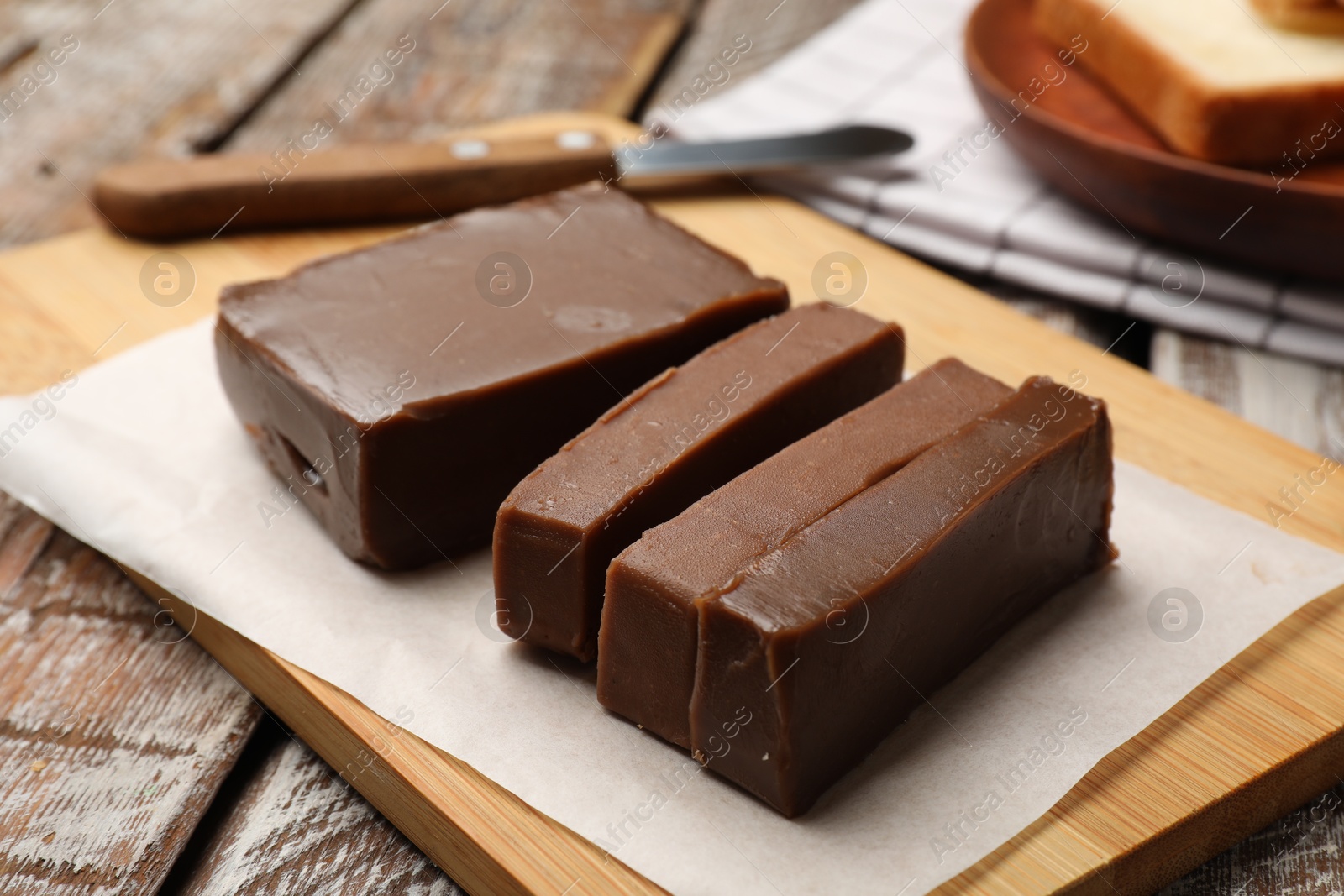 Pieces of tasty chocolate butter and knife on wooden table, closeup Photo of Pieces of tasty chocolate butter and knife on wooden table, closeup