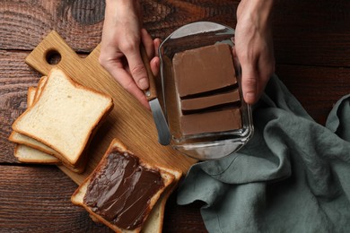 Photo of Woman with tasty chocolate butter and knife at wooden table, top view