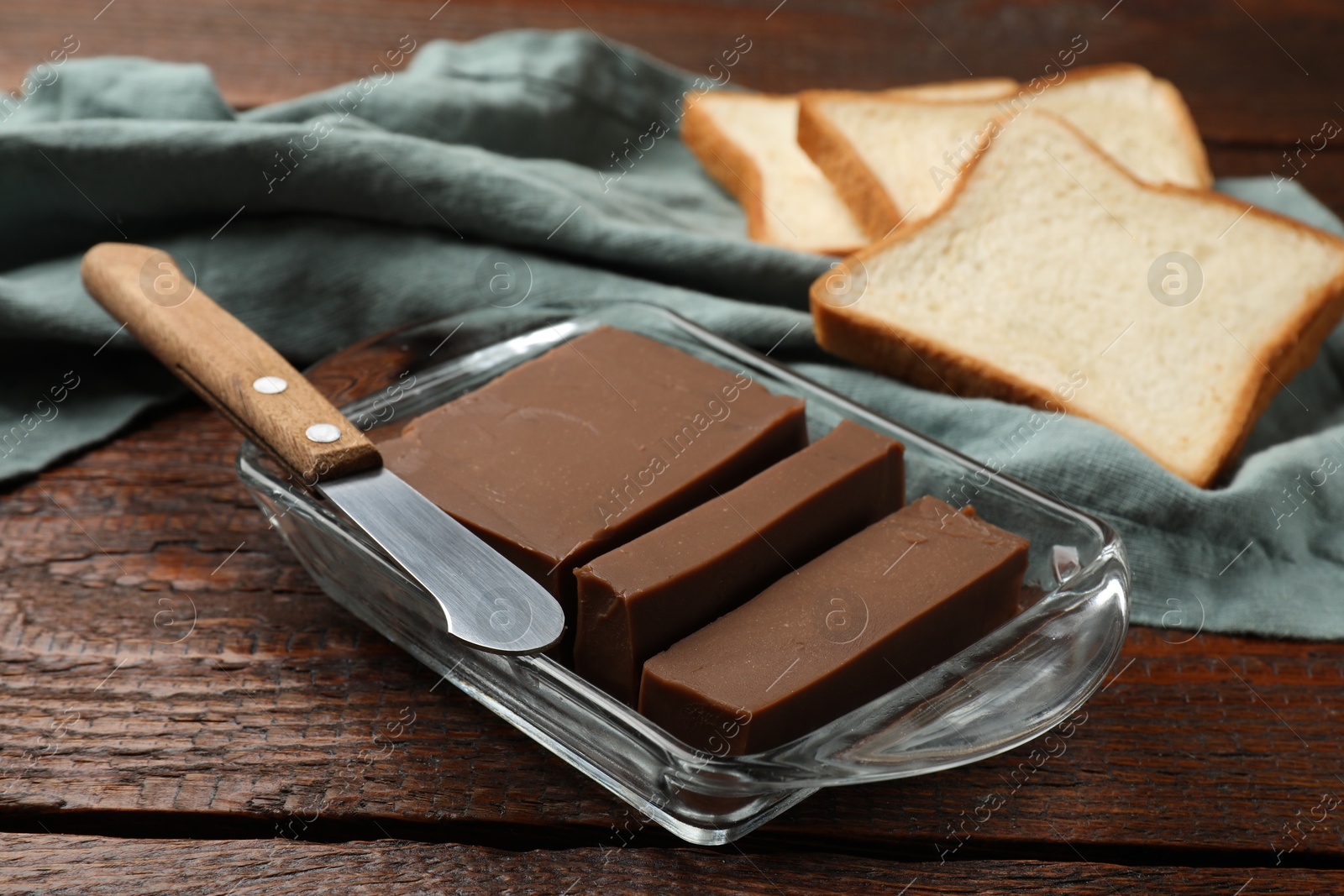 Tasty chocolate butter, slices of bread and knife on wooden table, closeup Photo of Tasty chocolate butter, slices of bread and knife on wooden table, closeup
