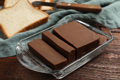 Photo of Tasty chocolate butter, slices of bread and knife on wooden table, closeup