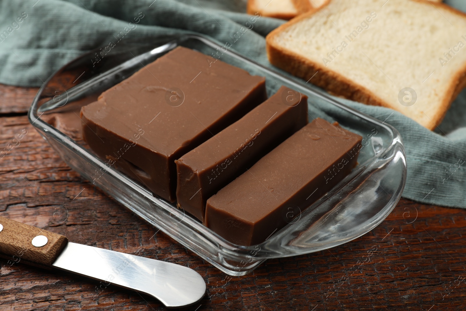Tasty chocolate butter, slice of bread and knife on wooden table, closeup Photo of Tasty chocolate butter, slice of bread and knife on wooden table, closeup