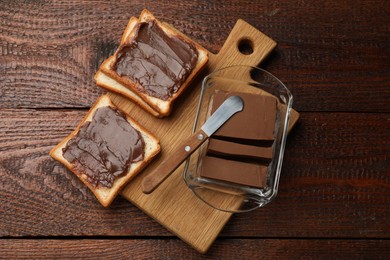 Photo of Tasty chocolate butter, slices of bread and knife on wooden table, top view
