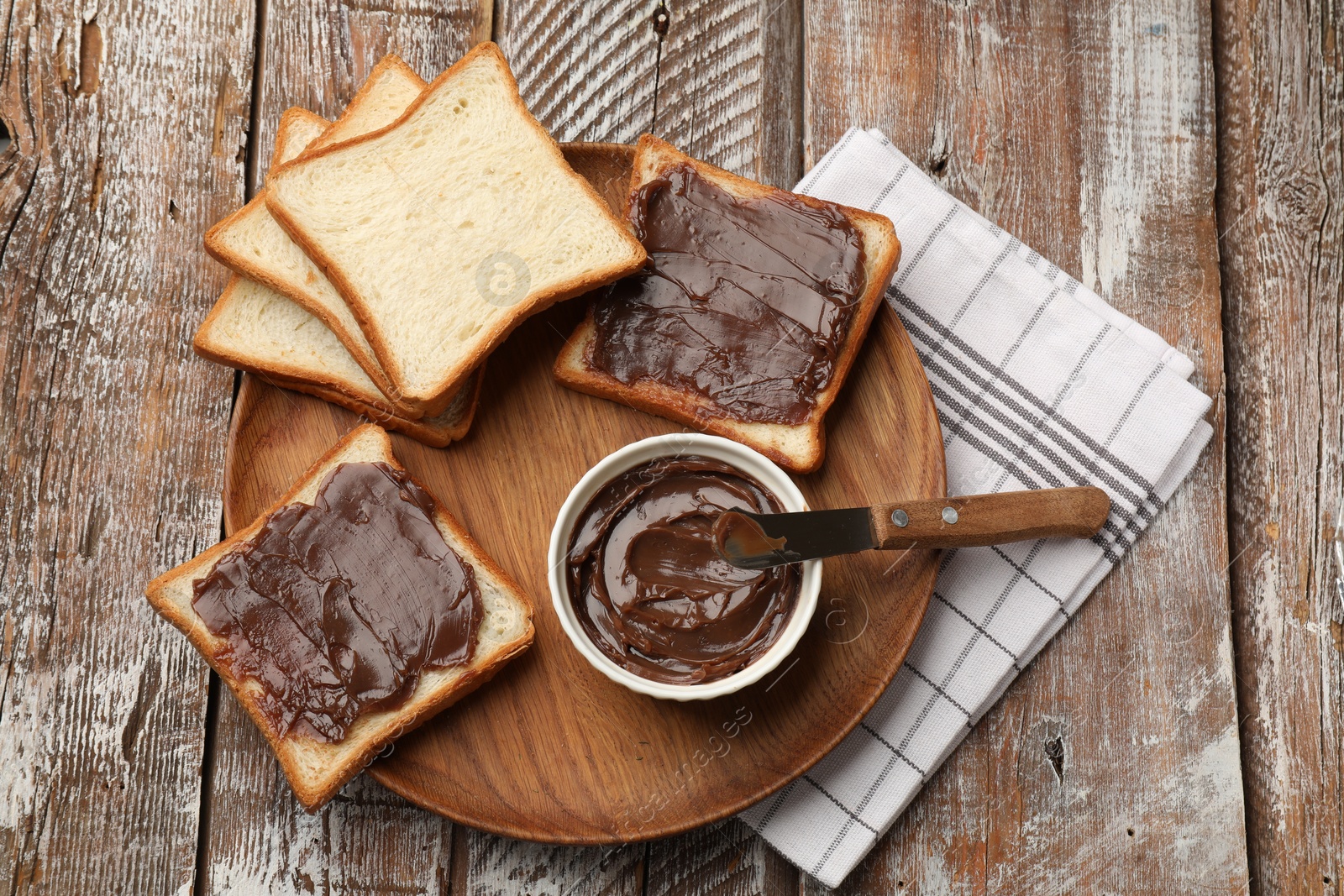 Tasty chocolate butter, slices of bread and knife on wooden table, top view Photo of Tasty chocolate butter, slices of bread and knife on wooden table, top view