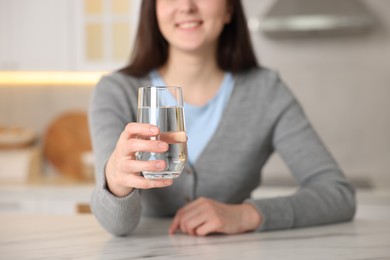 Photo of Woman with glass of water at white marble table in kitchen, closeup
