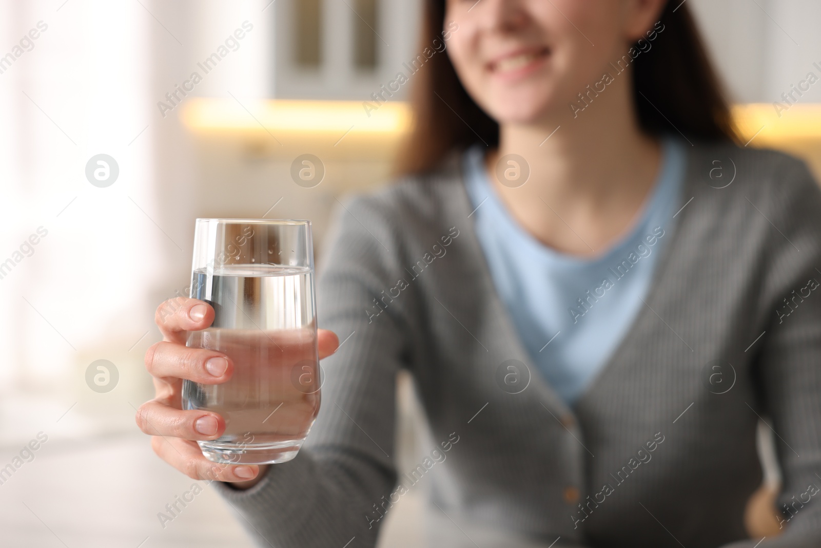 Woman with glass of water in kitchen, selective focus Photo of Woman with glass of water in kitchen, selective focus