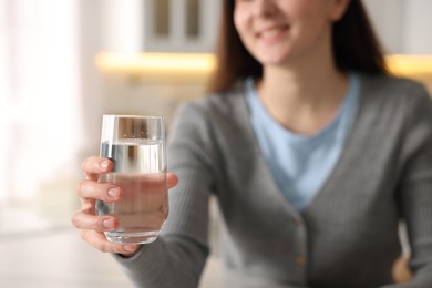 Photo of Woman with glass of water in kitchen, selective focus