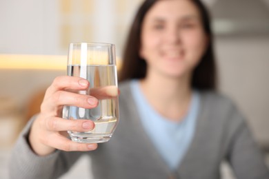 Photo of Woman with glass of water in kitchen, selective focus