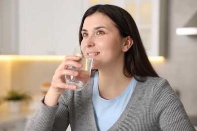 Photo of Woman drinking water from glass in kitchen