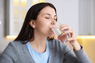 Photo of Woman drinking water from glass in kitchen