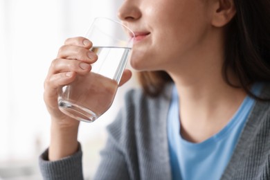 Photo of Woman drinking water from glass in kitchen, closeup