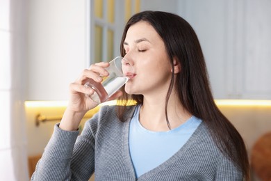 Photo of Woman drinking water from glass in kitchen