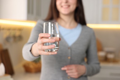 Photo of Woman with glass of water in kitchen, selective focus