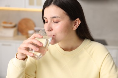 Photo of Woman drinking water from glass in kitchen