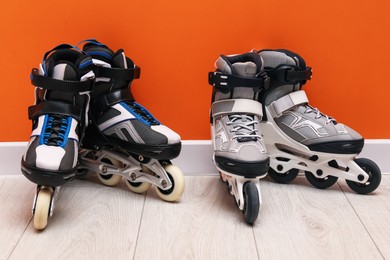 Photo of Pairs of roller skates on floor near orange wall
