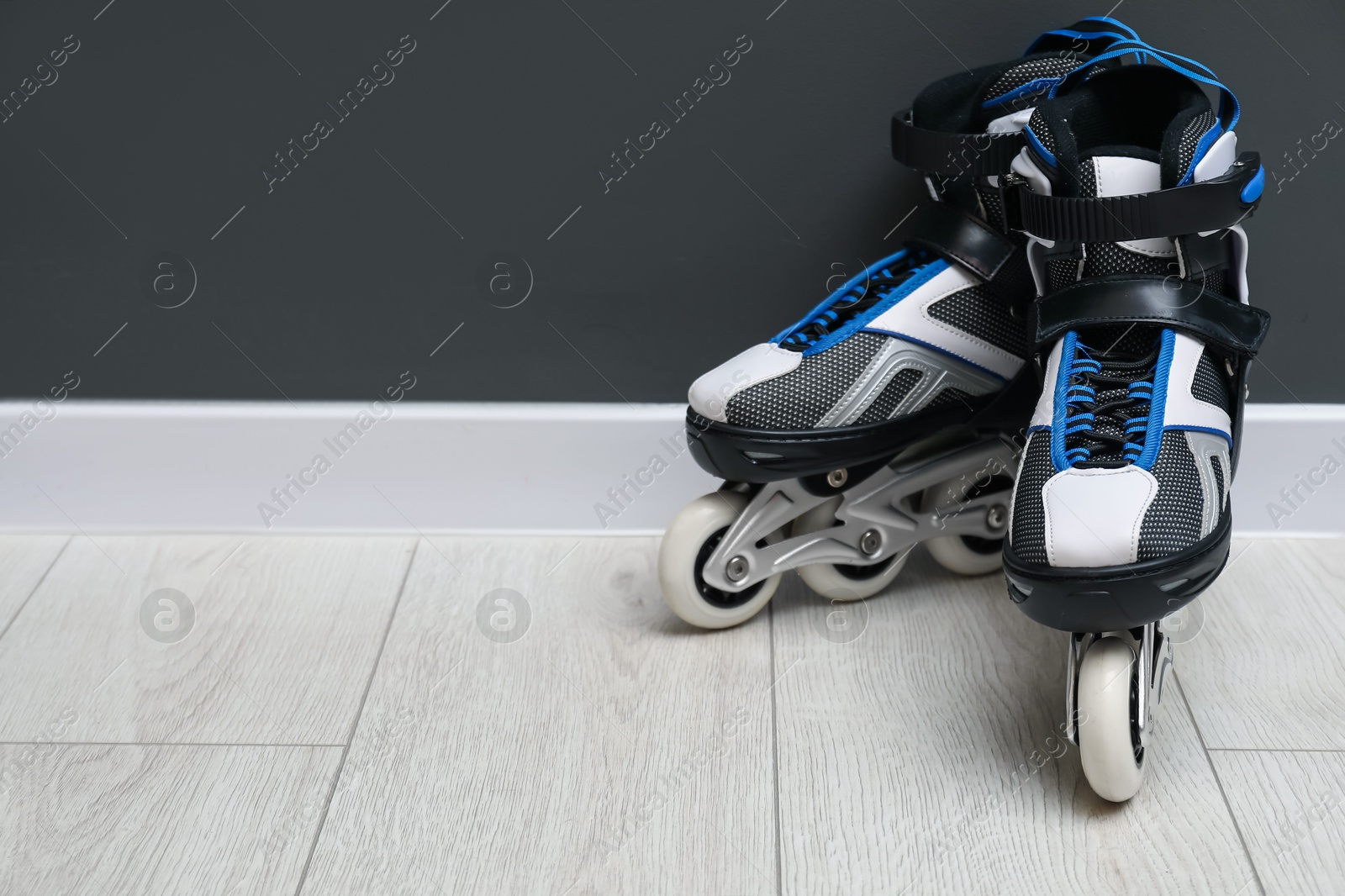Pair of roller skates on floor near black wall, space for text Photo of Pair of roller skates on floor near black wall, space for text