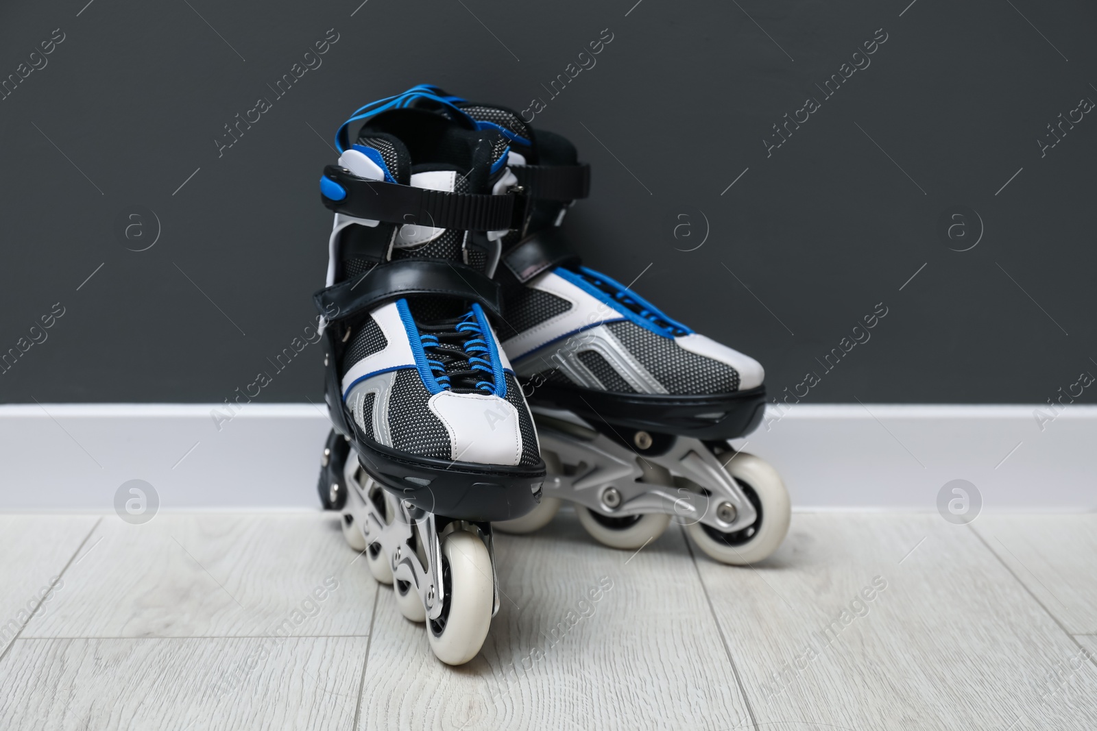 Pair of roller skates on floor near black wall Photo of Pair of roller skates on floor near black wall