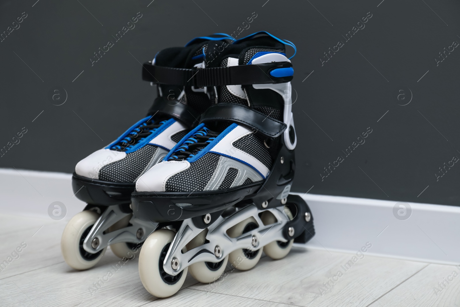 Pair of roller skates on floor near black wall, space for text Photo of Pair of roller skates on floor near black wall, space for text