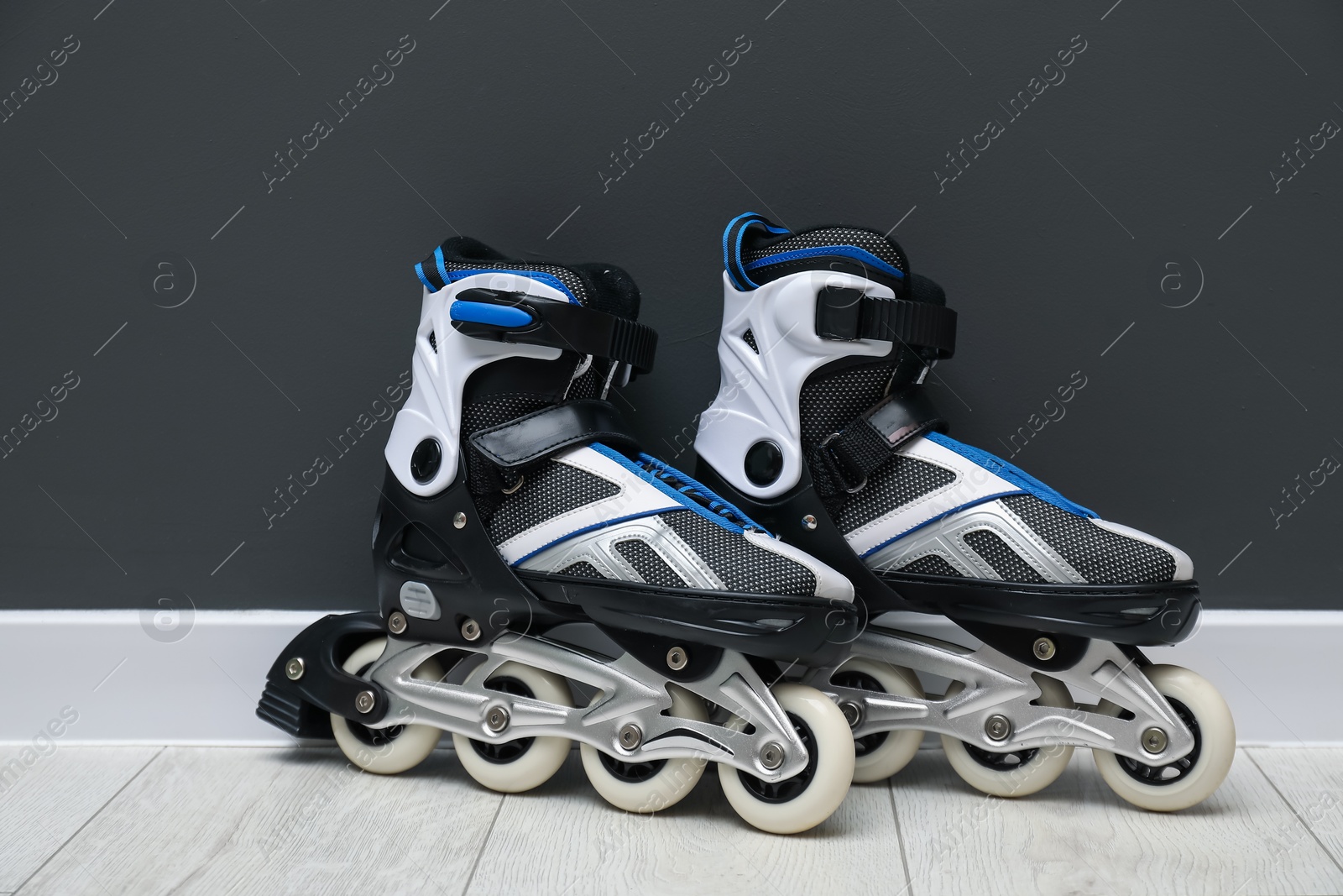 Pair of roller skates on floor near black wall Photo of Pair of roller skates on floor near black wall
