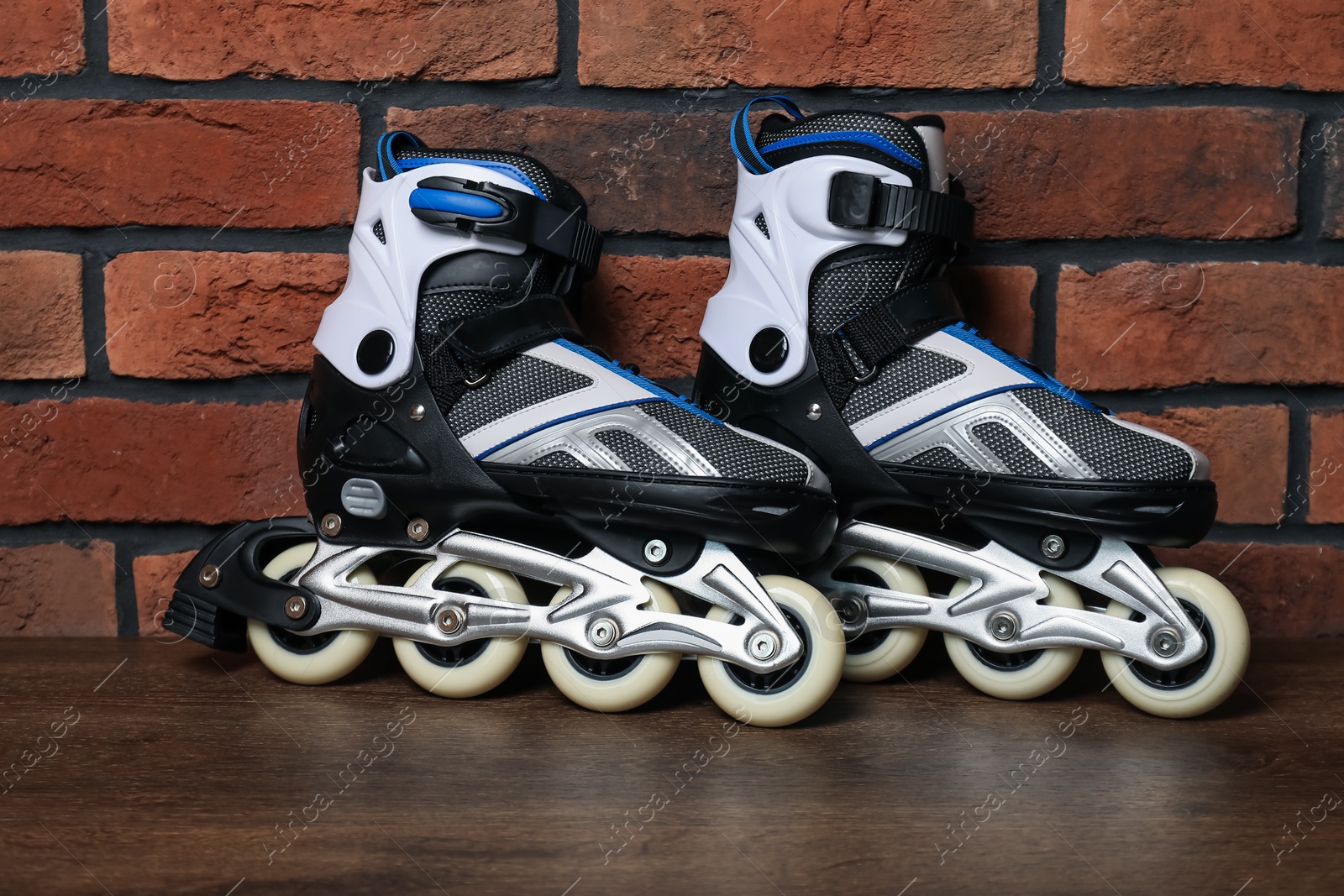 Pair of roller skates on wooden table near brick wall Photo of Pair of roller skates on wooden table near brick wall