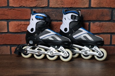 Photo of Pair of roller skates on wooden table near brick wall