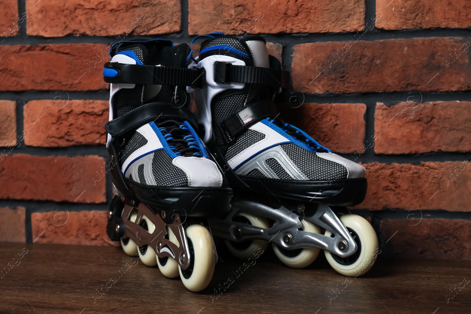 Pair of roller skates on wooden table near brick wall Photo of Pair of roller skates on wooden table near brick wall