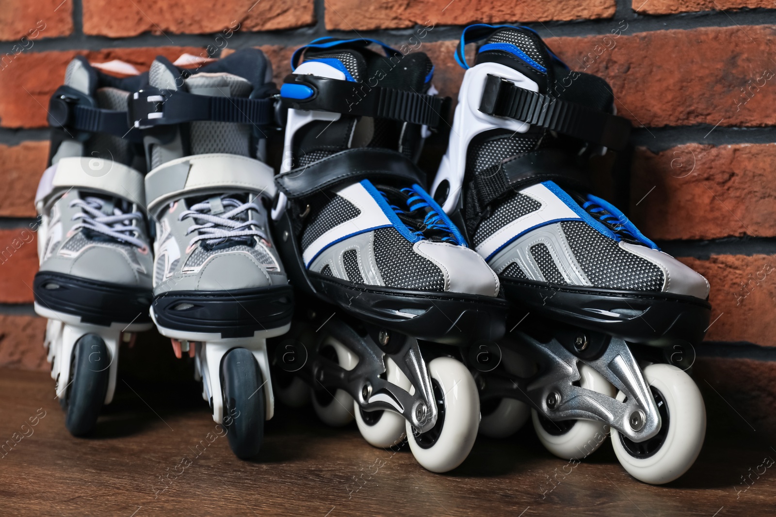 Pairs of roller skates on wooden table near brick wall, closeup Photo of Pairs of roller skates on wooden table near brick wall, closeup
