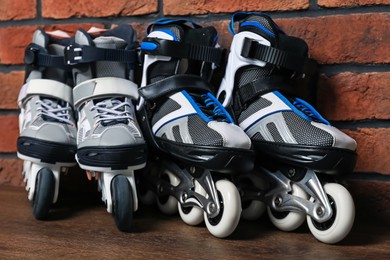 Photo of Pairs of roller skates on wooden table near brick wall, closeup