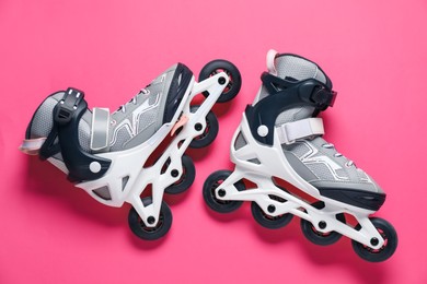 Photo of Pair of roller skates on pink background, top view