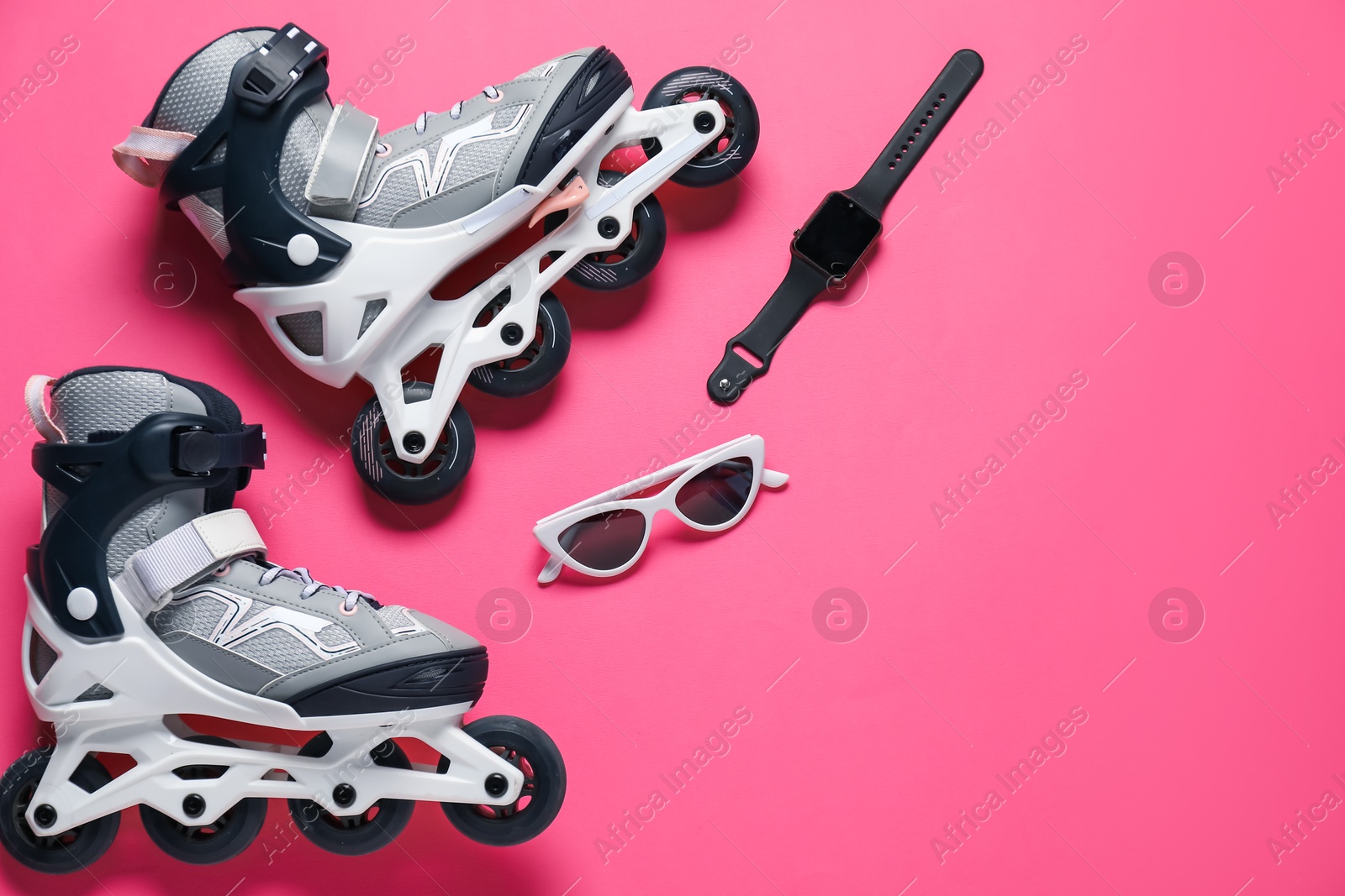 Pair of roller skates, watch and sunglasses on pink background, flat lay. Space for text Photo of Pair of roller skates, watch and sunglasses on pink background, flat lay. Space for text