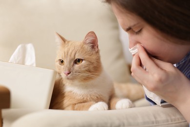 Photo of Woman suffering from allergy with her cat at home, closeup