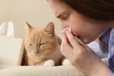 Photo of Woman suffering from allergy with her cat at home, closeup