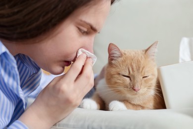 Photo of Woman suffering from allergy with her cat at home, closeup