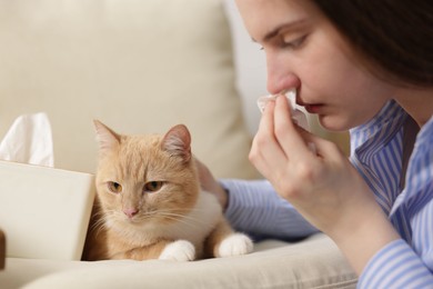 Photo of Woman suffering from allergy with her cat at home, closeup