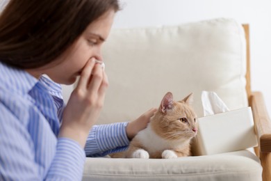 Photo of Woman suffering from allergy with her cat at home