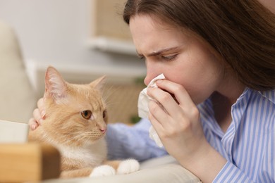 Photo of Woman suffering from allergy with her cat at home