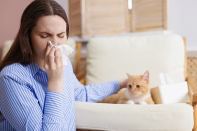 Photo of Woman suffering from allergy with her cat at home, selective focus