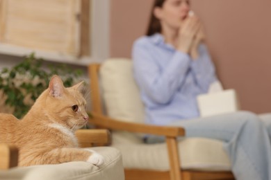 Photo of Woman suffering from allergy with her cat at home, selective focus