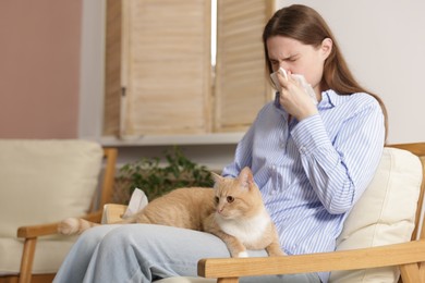 Photo of Woman suffering from allergy with her cat in armchair at home