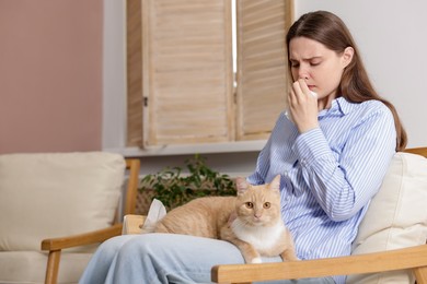 Photo of Woman suffering from allergy with her cat in armchair at home