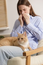 Photo of Woman suffering from allergy with her cat in armchair at home