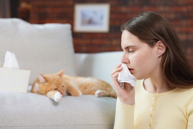 Photo of Woman suffering from allergy with her cat at home, selective focus