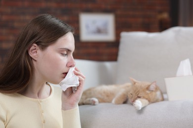 Photo of Woman suffering from allergy with her cat at home, selective focus